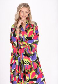 Färgglad kimono med stora abstrakta mönster i rött, grönt, lila och svart; tillverkad av lätt tyg med vida ärmar.