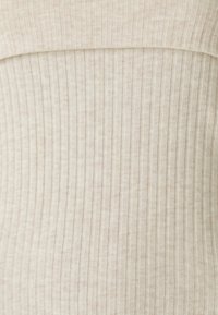 Top a coste in tessuto beige chiaro, con scollatura liscia e una texture morbida. Il design è aderente con strisce verticali.