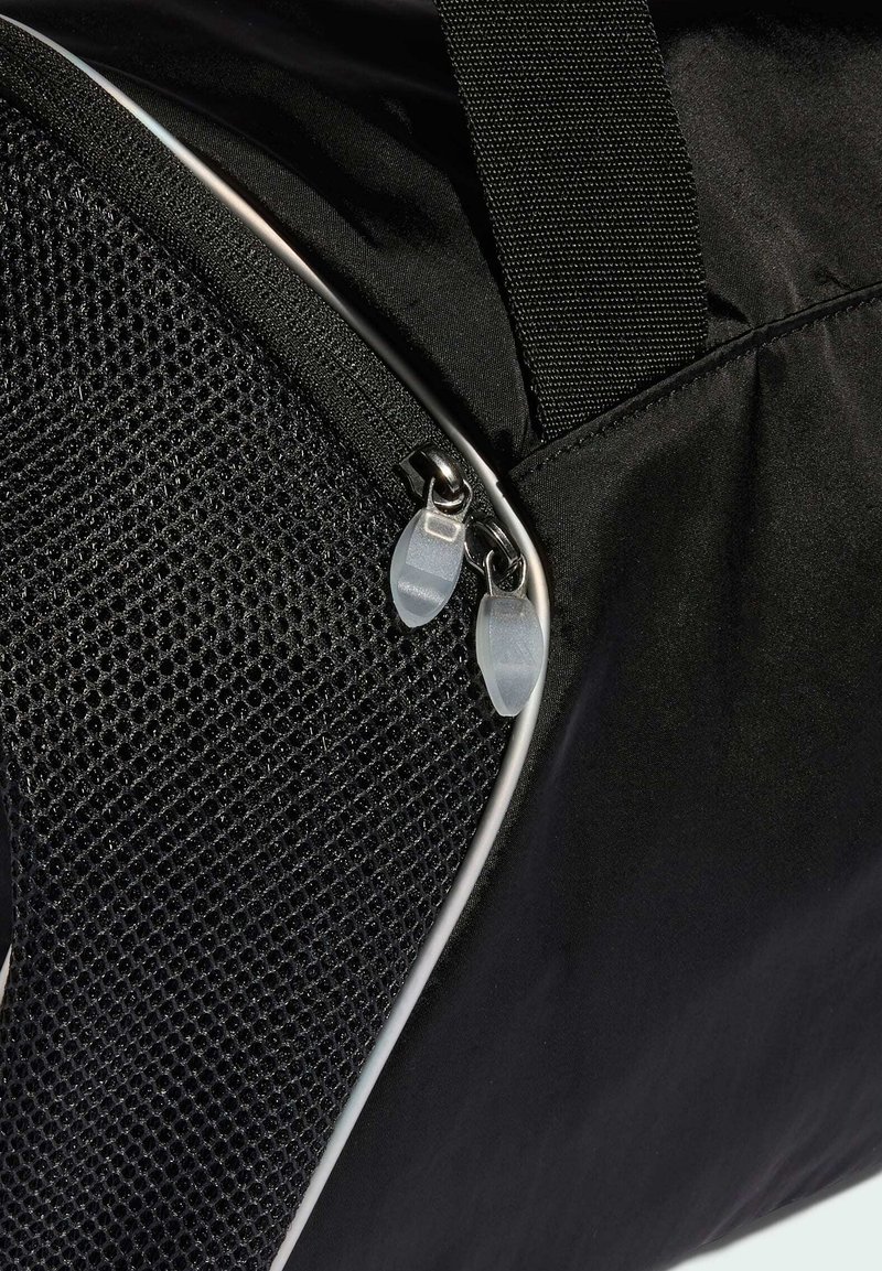 Schwarze Stofftasche mit strukturiertem Netzfach und zwei dicht beieinanderliegenden silbernen Reißverschlüssen mit durchsichtigen Zuglaschen.