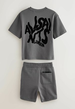 Grijze katoenen tweedelige set bestaande uit een T-shirt met korte mouwen en zwarte grafische tekst, en een short met een elastische tailleband en een achterzak.