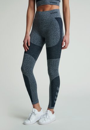 Leggings atletici grigi con dettagli in contrasto blu navy, vita alta e tessuto testurizzato. Presentano un logo e accenti geometrici sul lato.
