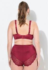 Burgunderfarbenes Dessous-Set mit einem gerippten BH und hochgeschnittenen Panties mit Spitzendetails. Verstellbare Träger und Haken- und Ösenverschluss sichtbar.