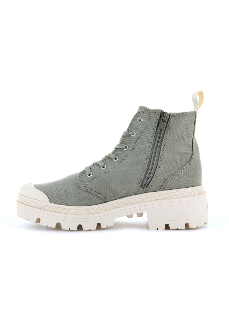 Botas de tobillo de lona verde claro con punta redondeada, suela de goma blanca, cremallera lateral y puntera reforzada. Presentan un diseño de cordones y una pestaña en la parte superior.