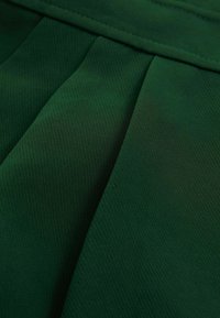 Tumeroheline kangas nähtavate õmbluste ja voldikutega, mis näitab tekstuuri ja voltimisi lähivõttes.