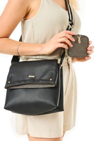 Borsa a tracolla nera con texture, dotata di un pattina ribaltabile e dettagli dorati, abbinata a una piccola pochette nera con motivo dorato.