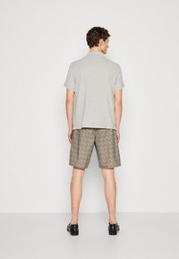 Ανδρικό γκρι πόλο μπλουζάκι σε συνδυασμό με καρό μπεζ σορτς που διαθέτουν επαναλαμβανόμενο σχέδιο λογοτύπου. Το σύνολο ολοκληρώνεται με μαύρα παπούτσια.