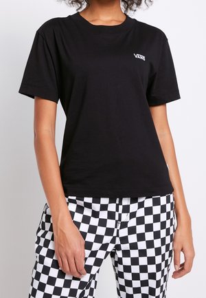 Schwarzes Baumwoll-T-Shirt mit kurzen Ärmeln, einem Rundhalsausschnitt und einem weißen Vans-Logo auf der Brust, kombiniert mit schwarz-weiß karierten Hosen.