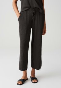 Pantalons en tissu froissé gris foncé avec une taille élastique et un cordon de serrage, dotés de poches latérales et d'un design décontracté à jambe droite.