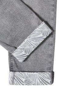 Jean en denim gris avec des revers pliés révélant une doublure en tissu blanc avec un motif abstrait de feuilles grises.