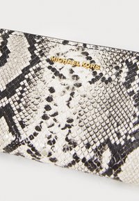 Černá a bílá peněženka se vzorem hadí kůže s hladkým povrchem, s akcentem zlatého loga "Michael Kors".