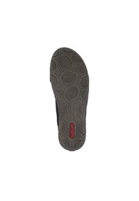 Baskets noires avec une semelle en caoutchouc texturé présentant des motifs hexagonaux. Marque en rouge embossée sur la semelle. Partie supérieure lisse.