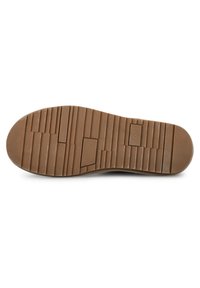 Suela de zapato de goma marrón con patrón texturizado, que presenta surcos y crestas para un mejor agarre. Marca mínima en el lateral.