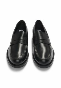 Black leather loafers with a smooth finish, featuring a decorative strap across the front and minimalistic design. Sole is slightly raised.