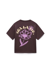 Mørkebrun kortermet skjorte med stor lilla blomstergrafikk og kremfarget tekst "SEA LA VIE." buet over blomsten på baksiden.