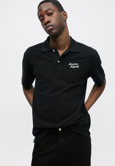 Juodas polo marškinėlis su tekstūruotu audiniu, turintis tris mygtukus ir baltą išsiuvinėtą "Maison Kitsuné" logotipą ant krūtinės.