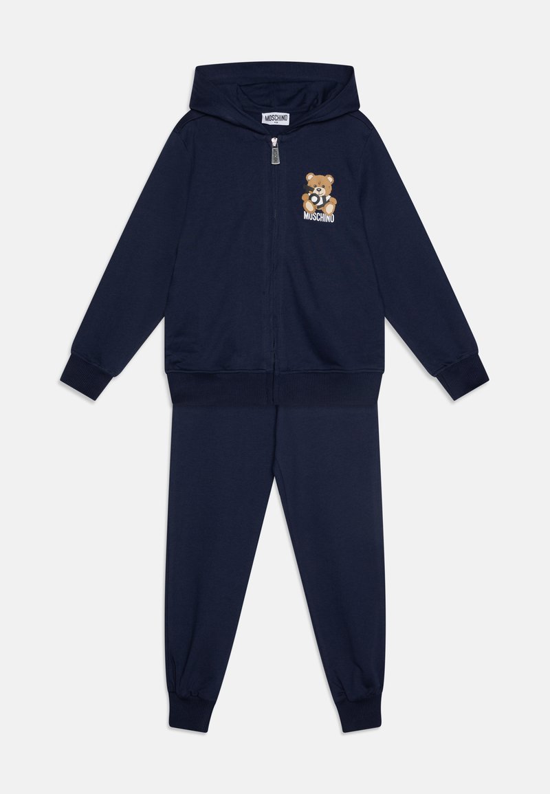 Temno modri trenirki, izdelani iz mehkega materiala, z zip-up kapuco, ki ima grafiko medveda, in elastičnimi manšetami na hlačah za boljši oprijem.
