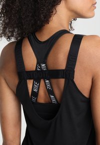 Débardeur de sport noir avec un design dos nageur, arborant les inscriptions "JUST DO IT" et "NIKE" sur les bretelles, et une coupe ample.