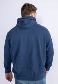 Felpa con cappuccio blu navy, maniche lunghe, tessuto testurizzato e polsini e orlo a costine. Presenta un grande cappuccio e un design semplice.