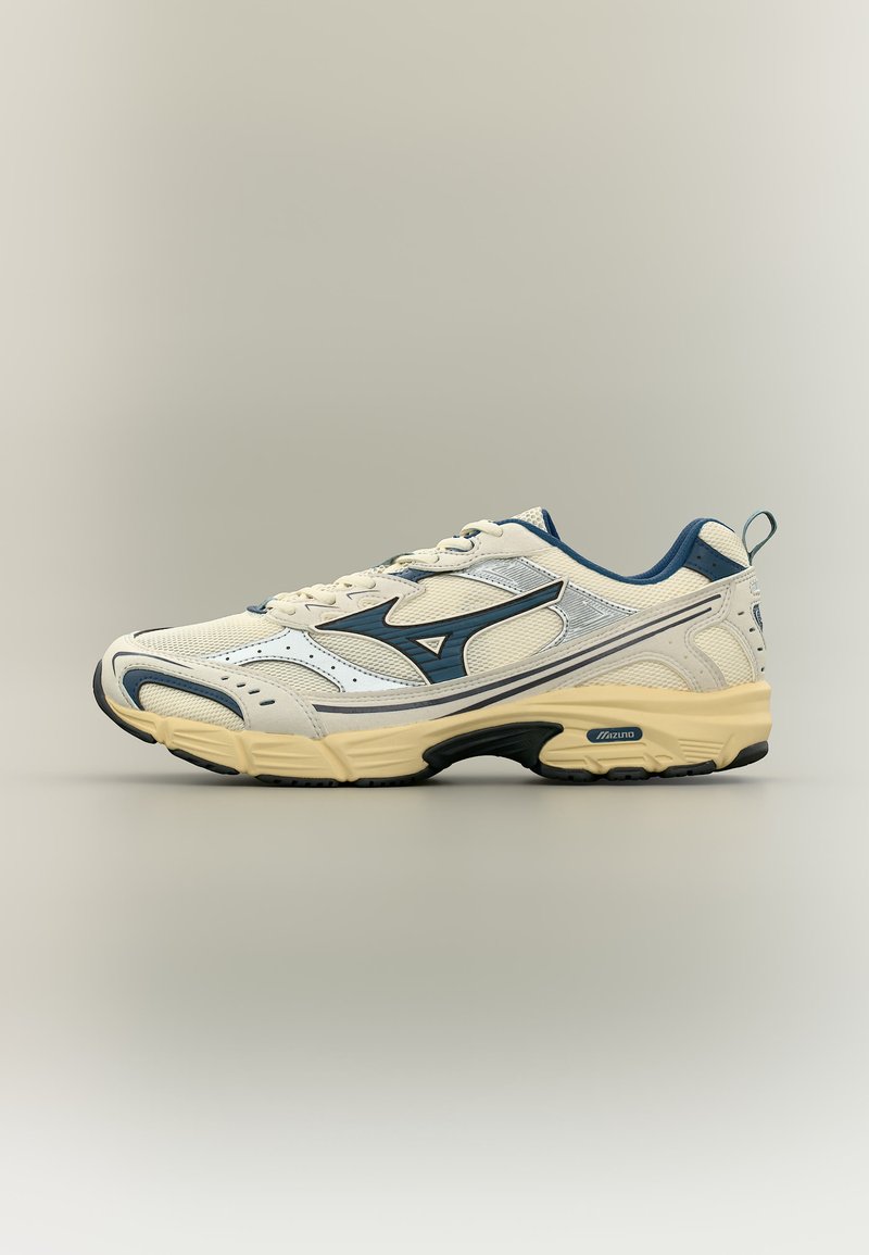 Hvit og mørkeblå atletisk joggesko med beige såle, nettstoff på overdelen og Mizuno-logo på siden, vist i profil mot en nøytral bakgrunn.
