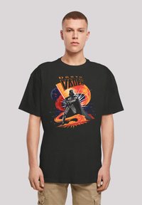 Mustat puuvillapaitat, joissa on graafinen printti Darth Vaderista, eloisan oranssin ja sinisen korostuksen kera, esittelee monimutkaisia suunnittelu-elementtejä.