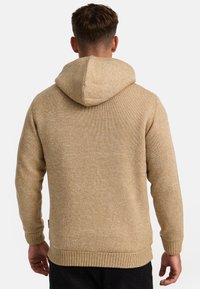 Sudadera con capucha en un tejido texturizado color beige, con puños y dobladillo acanalados, de ajuste holgado y con una vista trasera que muestra la capucha.
