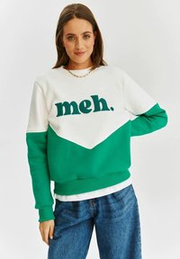 Mikina s designem v bílé a zelené barvě kombinovaným do bloků. Na přední straně se nachází výrazné, strukturované písmo "meh.". Vyrobena z měkkého materiálu a má volný střih.