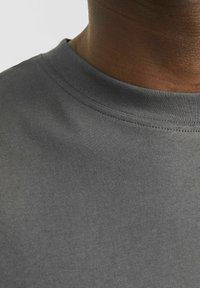 Grå bomuld t-shirt med ribbet rund hals, glat tekstur og en tætsiddende pasform, der viser et tæt billede af stoffet og kraven.