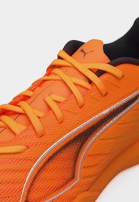 Φωτεινό πορτοκαλί αθλητικό παπούτσι με κορδόνια στο ίδιο χρώμα, μαύρο και ασημί λογότυπο Puma και μαύρη εσωτερική επένδυση.