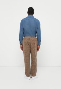 Denim shirt and brown patterned pants feature a drawstring waist and back pocket with logo. Pants have a subtle animal print design.