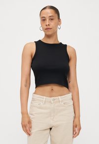 Fekete, rövidített tanktop bordázott anyagból, kerek nyakkivágással és ujjatlan kivitelezéssel. Világos bézs, magas derekú nadrággal párosítva.