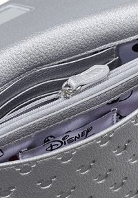 Silberne Handtasche mit Textur und Reißverschlussfach, ausgestattet mit einem gemusterten Innenraum mit Disney-Branding und kleinen, runden Akzenten.