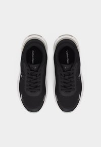 Μαύρα αθλητικά παπούτσια Calvin Klein με λευκές σόλες, σε άποψη από πάνω, με κορδόνια και εσωτερικές σόλες με επωνυμία.