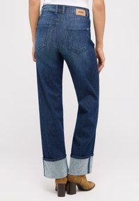 Dunkelblaue Jeans aus Denim im geraden Schnitt, mit hochgekrempelten Säumen, die helleren Denim zeigen, und einem Leder-Label auf dem hinteren Bund.