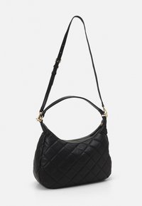 Quilted black leather shoulder bag with a curved silhouette, gold-tone hardware, and a detachable adjustable strap. Zippered opening at the top.