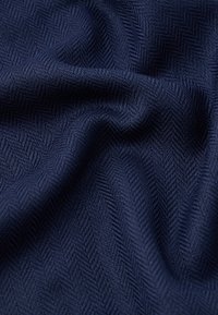 Námornícká farba herringbone látky s textúrovaným, tkaným vzorom. Mäkký a mierne lesklý povrch, zavesený tak, aby ukázal hĺbku a zložitosti tkania.