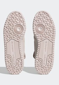 Light pink rubber sneaker soles with a textured pattern, featuring circular accents and grooves for traction. No visible branding on the soles.