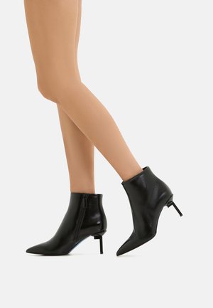 Stivali neri in pelle fino alla caviglia con punta affusolata, tacco a stiletto sottile e dettagli con zip laterale; finitura lucida e silhouette elegante.