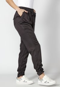Pantalons de jogging noirs avec une taille élastique, des poches latérales et des ourlets froncés. Fabriqués en tissu doux, associés à des chaussures blanches ornées d'étoiles argentées.