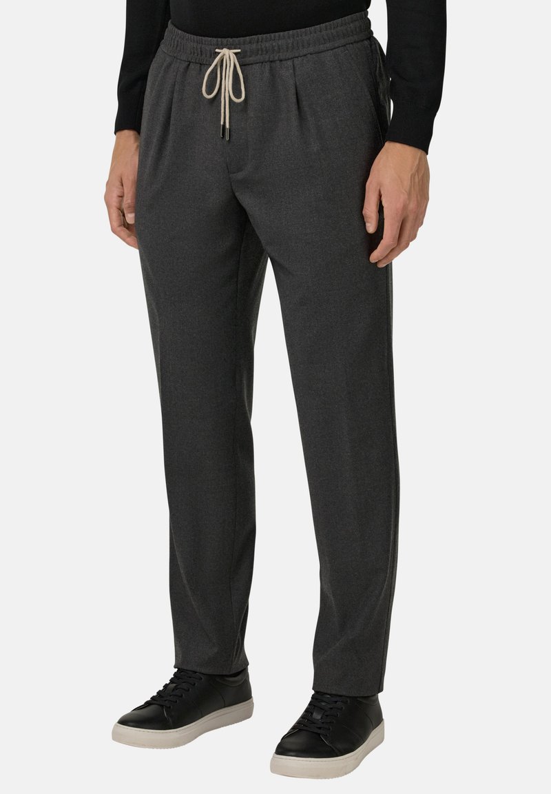 Tamsiai pilki siauri kelnių, pagaminti iš minkštos medžiagos, su elastinga juostele ir raišteliu, bei šoninėmis kišenėmis. Su juodais kedais.