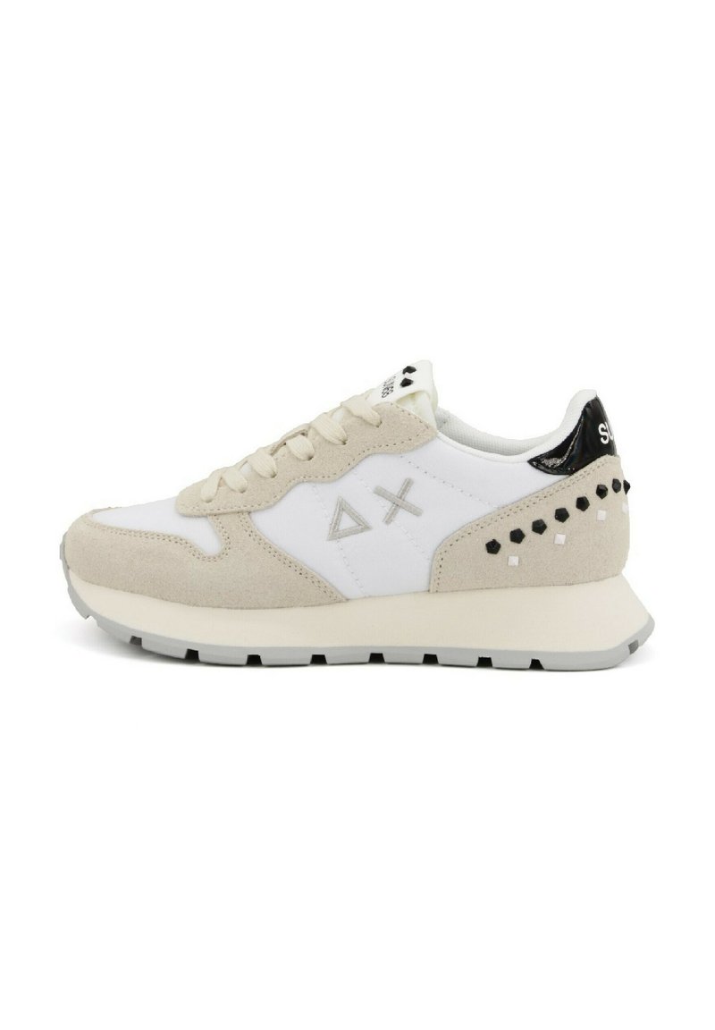 Sneaker bianca con dettagli in suede beige, caratterizzata da design geometrici, dettaglio del tallone nero e adornamenti a borchie sui lati.