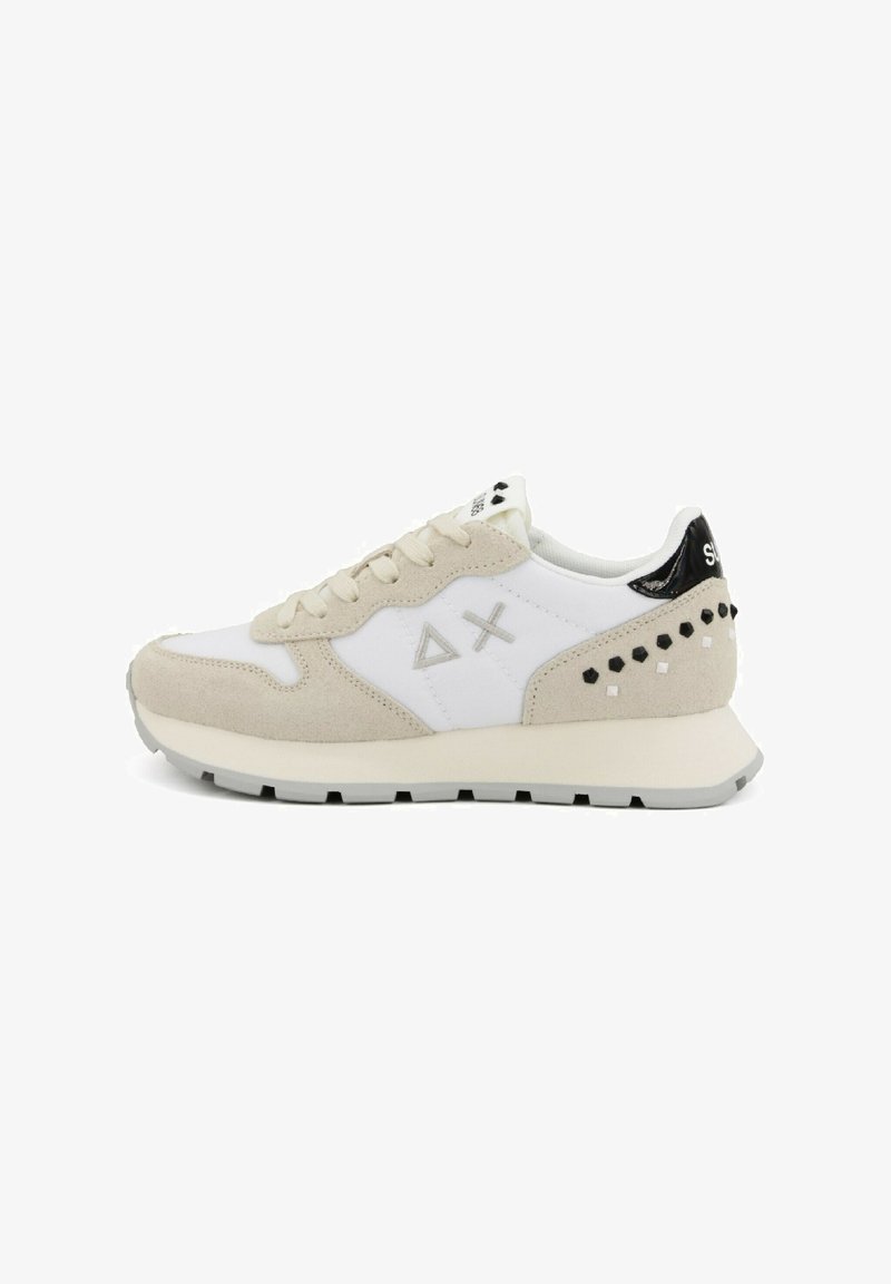 Witte sneaker met beige suède accenten, voorzien van geometrische ontwerpen, zwarte hiel detail en gestructureerde embellissements aan de zijkant.