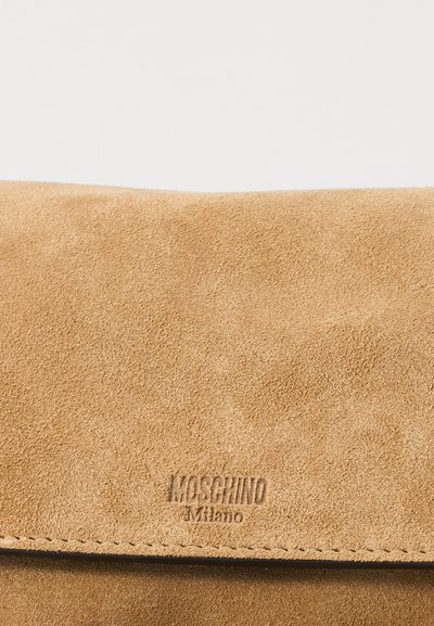 Σουέτ επιφάνεια σε ταμπά απόχρωση με ραμμένη άκρη και ανάγλυφο λογότυπο Moschino Milano κεντραρισμένο κοντά στο κάτω μέρος.