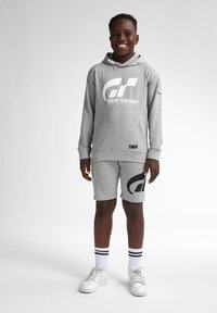 Šedá souprava s mikinou a šortkami, která se pyšní velkým černým logem "GT" a textem. Materiál vypadá jako měkká bavlněná směs; obsahuje kapuci se šňůrkou a kapsy.