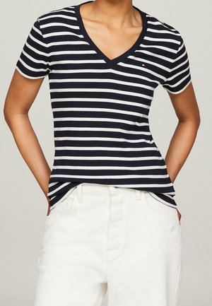 Laivastonsinivalkoraidallinen lyhythihainen V-kaula-aukollinen slim fit -t-paita pehmeää puuvillakangasta, yhdistettynä valkoisiin housuihin. Pieni logo rinnassa.