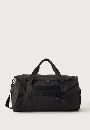 Bolsa de viaje negra con asas superiores, correa desmontable para el hombro, compartimentos con cremallera y un bolsillo delantero con una anilla metálica.