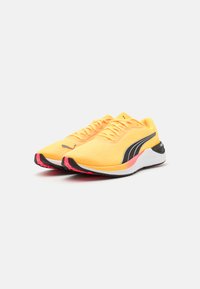 Scarpe da corsa gialle con una tomaia testurizzata, accenti laterali neri e suola rosa. I lacci sono ben visibili sopra.