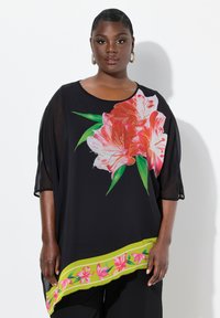 Túnica negra con un gran dise�ño floral en rosa y detalles verdes en el dobladillo. Tejido semitransparente, corte relajado y mangas cortas.