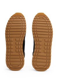 Suole di sneakers nere con un design in gomma testurizzata, caratterizzate da una suola tan con scanalature per aderenza e durata, e un marchio sul lato.