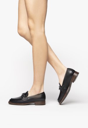 Black leather loafers with a rounded toe, decorative bow detail, and a low wooden heel. Smooth texture with a polished finish.