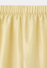 Hellgelber Rock mit gerafftem elastischem Bund und dezent gekrepter Stoffstruktur.